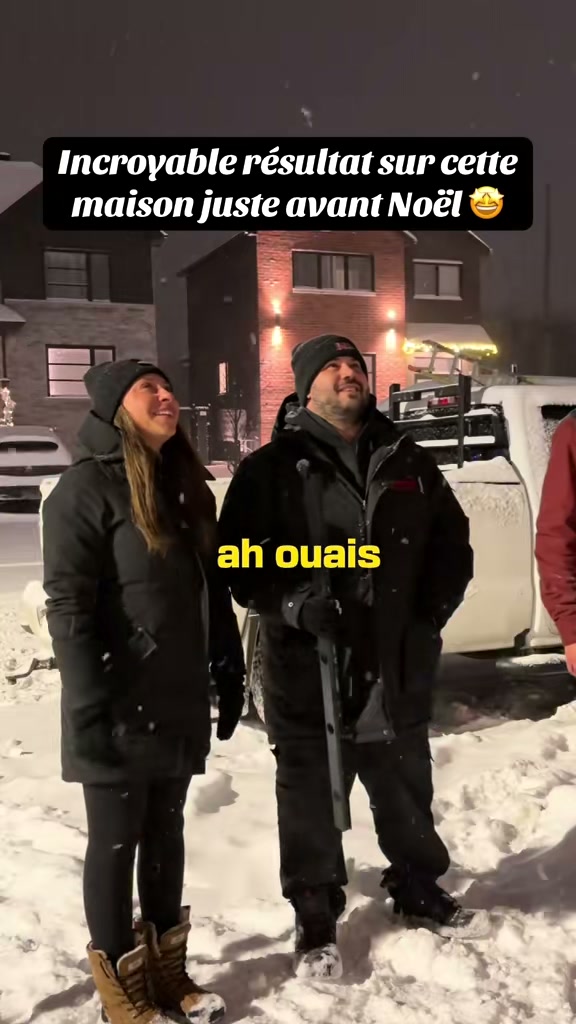 Un couple devant sa maison illuminée en blanc chaud, l’hiver, juste avant Noël
